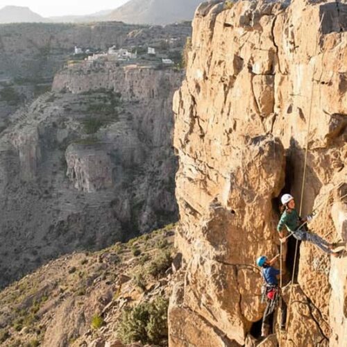 Un escursionista affronta il percorso attrezzato della via ferrata sulle imponenti pareti rocciose di Jebel Shams, Oman.