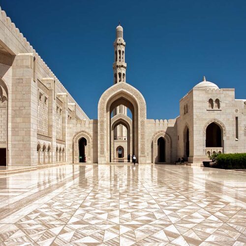 L'imponente portale d'ingresso principale in pietra scolpita della Grande Moschea del Sultano Qaboos a Mascate, Oman.
