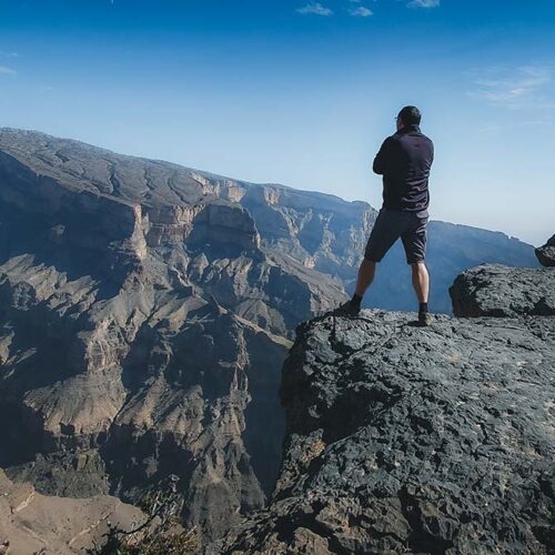 Un escursionista raggiunge la vetta del Jebel Shams, la montagna più alta dell'Oman a 3000 metri, lungo il sentiero W4 con vista sul Grand Canyon.