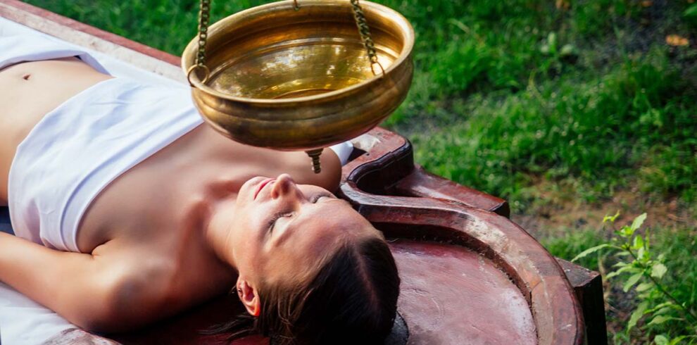 Primo piano di un massaggio ayurvedico tradizionale in una cabina spa rilassante e illuminata in modo soffuso.