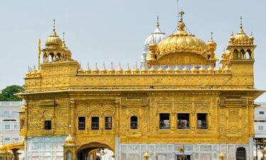 Stunning view of the Golden Temple reflecting in water on a sunny day in Amritsar, India.