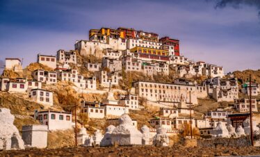 A stunning view of Thiksey Monastery against a warm sunset sky, showcasing its grandeur.