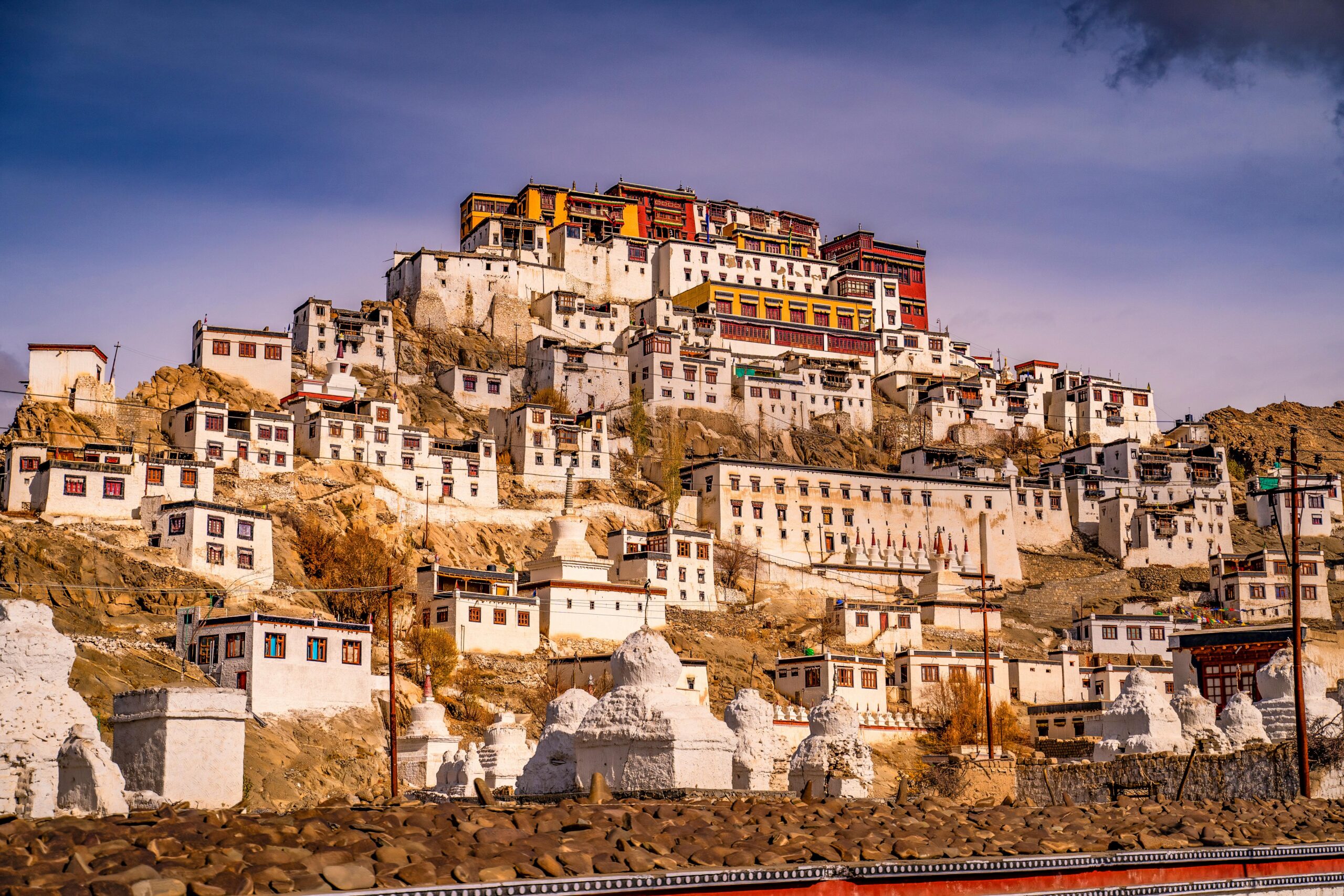 A stunning view of Thiksey Monastery against a warm sunset sky, showcasing its grandeur.