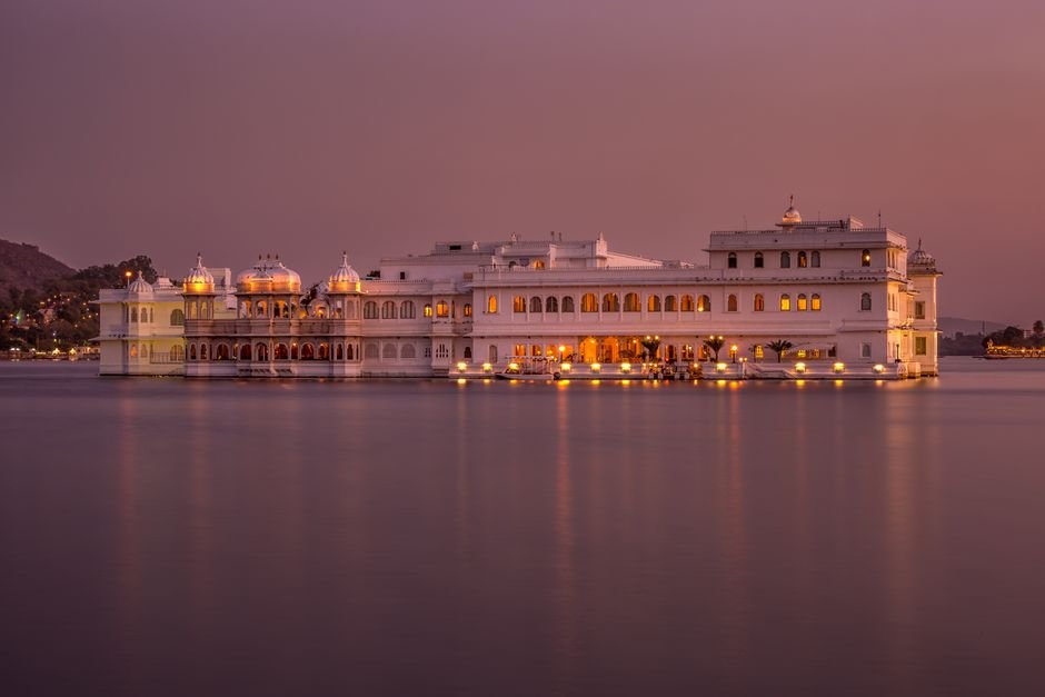 Stunning twilight view of Udaipur's Lake Palace illuminated, reflecting serene lake vibes.
